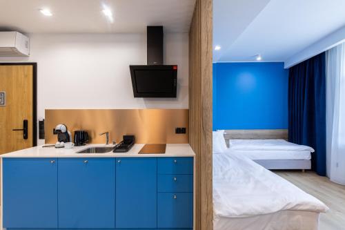 格丁尼亚SQUARE APARTMENTS GDYNIA的一间厨房,配有蓝色橱柜和一张位于客房内的床