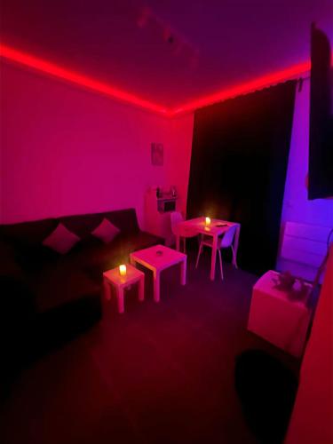 瑟兰La Suite Liege的客厅配有粉红色的灯和桌椅