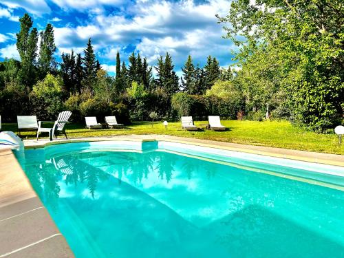 鲁西永Domaine Plan des Devens的一个带椅子的游泳池以及一个带树木的庭院