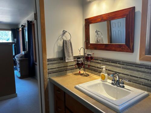 尼尔逊Kootenay, Lakeside Retreat, Main Floor and Walkout的浴室水槽配有镜子和2杯葡萄酒