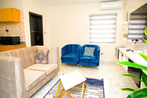 拉各斯U2 One Bedroom Apartment的客厅配有沙发和2把蓝色椅子
