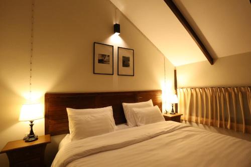 Bang ChakBaanrongmai Canal Front Cafe & Homestay的一间卧室配有一张带两盏灯的大型白色床。