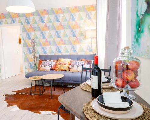 HésingueBasel Airport nature Stay的客厅配有沙发和带葡萄酒瓶的桌子