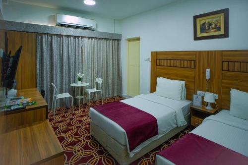 迪拜AL KARNAK HOTEL - BRANCH的酒店客房设有两张床和一张桌子。