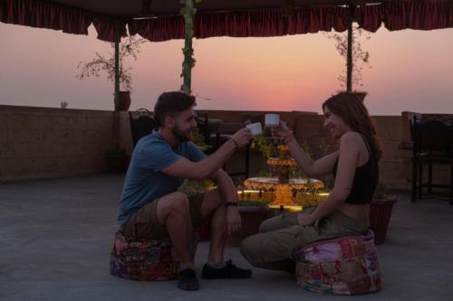 斋沙默尔Explore Hostel Life Jaisalmer的坐在桌子旁的男人和女人,拿着杯子