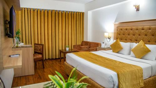 齐拉克普尔Hotel Dreamland Inn的酒店客房,设有一张带黄色窗帘的大床