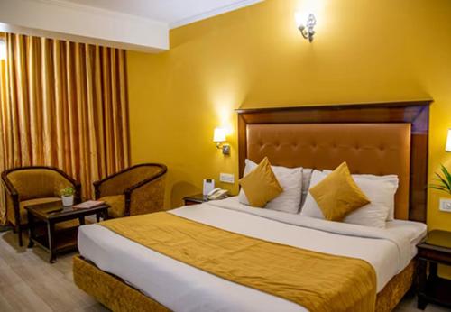 齐拉克普尔Hotel Dreamland Inn的酒店客房,设有一张黄色墙壁的大床