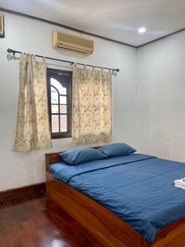 Ban NongdouangSaysouly Guest House的一间卧室配有一张带蓝色床单的床和一扇窗户。