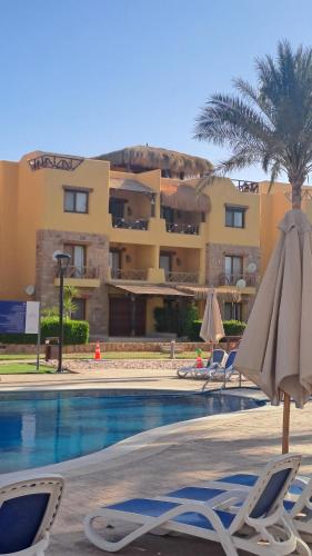 艾因苏赫纳Luxury Chalet in Mountain View 2 , El-Sokhna with Sea View , Pool View "Heated Pool" and Garden View Families Only的酒店设有带椅子和遮阳伞的游泳池