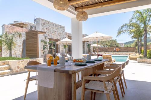 利萨基亚White Stone Luxury Villa的一个带桌椅的室外厨房和一个游泳池