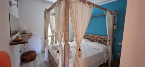 帕劳LOTUS Wellness Apartment - Resort Ginestre - Palau - Sardinia的一间卧室配有一张带窗帘的四柱床