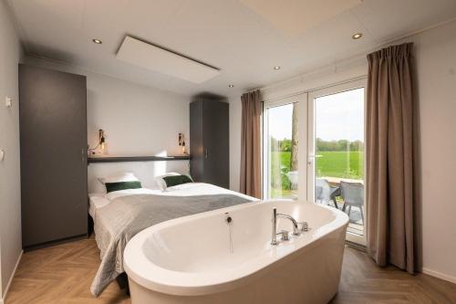 莱森Panorama lodge with wellness and hottub 2 p.的卧室配有一张床,床前设有浴缸