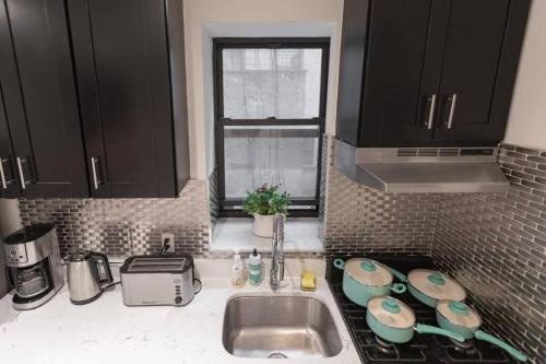 纽约Magnificent 5 Bedroom Apt in NYC!的厨房配有黑色橱柜、水槽和窗户。