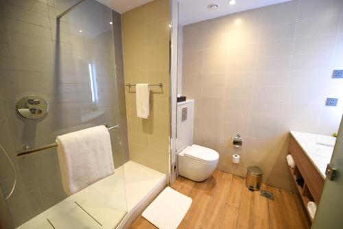 坎帕拉Hilton Garden Inn Kampala的一间带卫生间和玻璃淋浴间的浴室