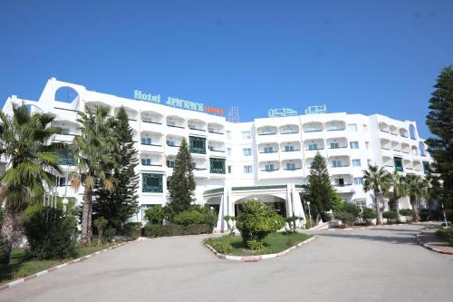 苏塞Hotel Jinene Resort的一间大型的白色酒店,前面有棕榈树