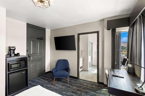 埃尔金斯Tygart Hotel, Ascend Hotel Collection的酒店客房带蓝色椅子和电视