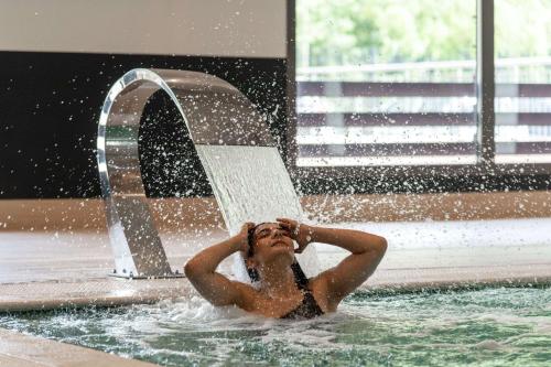 蒙彼利埃Zenitude Hotel la Valadiere, Ascend Hotel Collection的喷泉下游泳池里的女人