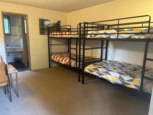 沃伯顿green gables warburton student camper accomodation的客房设有两张双层床和一张桌子。