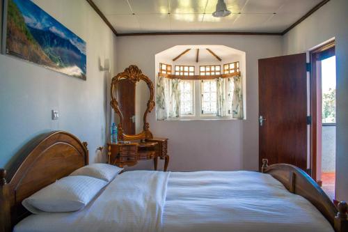 努沃勒埃利耶玛丽山宾馆的一间卧室配有一张床、镜子和窗户