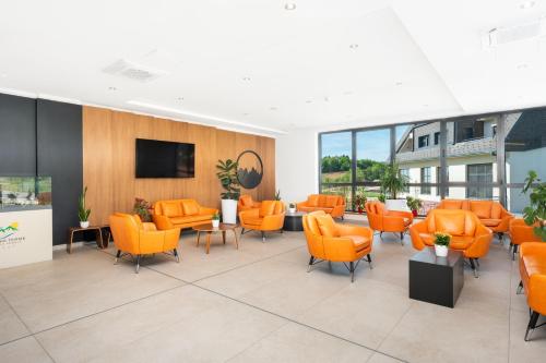 维尔蒂尼克Fruške Residences的一间配备有橙色椅子和平面电视的等候室