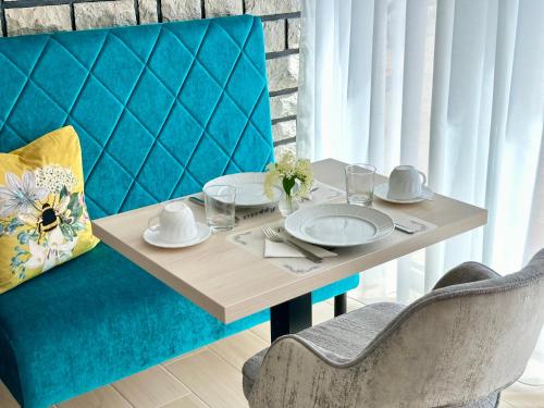 维斯普雷姆Éllő Residence的一张带盘子和餐巾的桌子,放在蓝色椅子上
