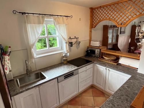 鲍道乔尼特尔代米茨ALPHA的厨房配有白色橱柜、水槽和窗户。