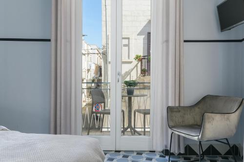 奥斯图尼Unico B&B Art Decor的一间带一张床和一把椅子的卧室以及一个阳台