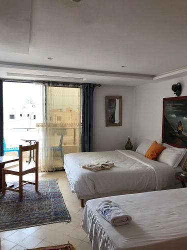 米勒福特Les Bains de Mirleft的一间卧室设有两张床、一张桌子和一个窗口
