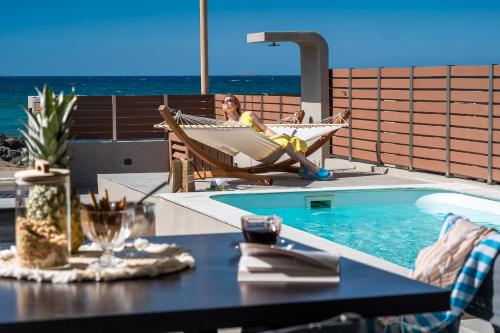 库基尼坎尼奥Anasa Luxury Villas的坐在游泳池旁的吊床上的女人