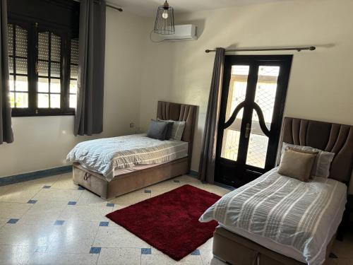 梅克内斯Dar el kebira的一间带两张床的卧室和红色地毯