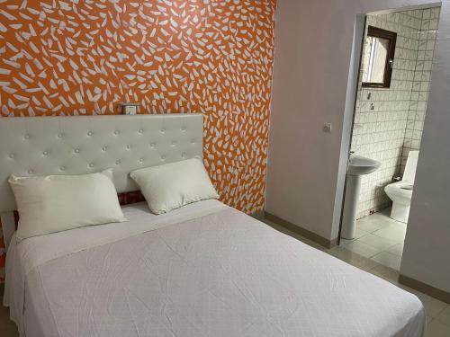 瓦加杜古Glorymienmo的一间卧室配有一张白色的床和橙色的墙壁