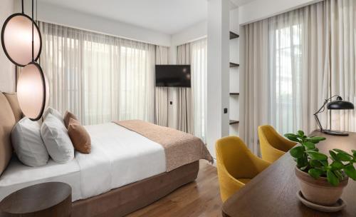 雅典The Residence Christokopidou Hotel & Spa的一间卧室配有一张床、一张桌子和一台电视。