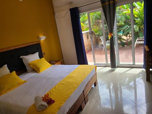 塔那那利佛Hotel Les Cygnes的一间卧室设有一张黄色墙壁的床和大窗户