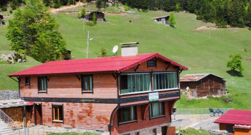乌宗Kalispera Apart Otel的山丘上一座木房子,屋顶红色