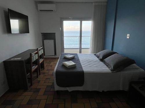 瓜拉派瑞Hotel Quatro Estações的一间卧室设有一张床,享有海景