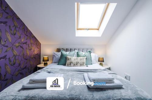 曼彻斯特4 Bedroom House Free Parking By NYOS PROPERTIES Short Lets & Serviced Accommodation Manchester的一间卧室配有一张带蓝色枕头的床和一扇窗户。