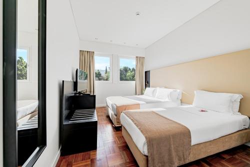 里斯本Lisboa Central Park Hotel Suites & Studios的酒店客房设有两张床和电视。