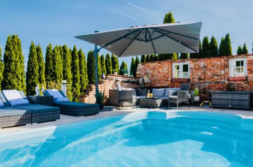 Aldersbach5 Sterne Centurion Ferienhaus Villa 2 Pools 86 Zoll TV的一个带遮阳伞和椅子的游泳池以及庭院