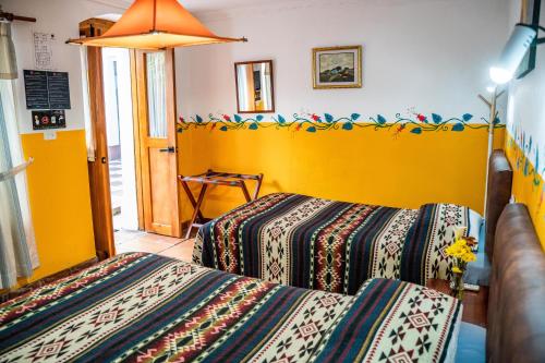 奥塔瓦洛Hostal Riviera Sucre的一间卧室设有两张床和黄色的墙壁