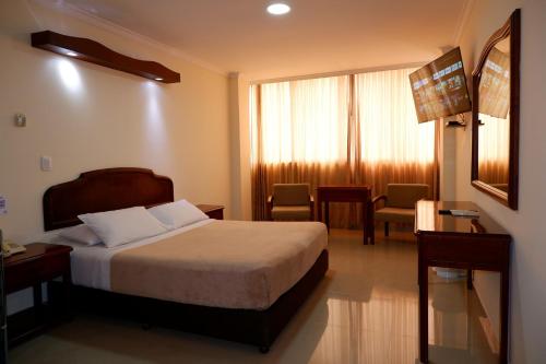 比亚维森西奥Hotel Maria Gloria的酒店客房带一张床、一张桌子和椅子