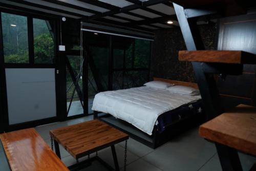 PadinjaratharaWetlands Wayanad Resort with Natural Waterfalls的卧室配有床、桌子和窗户。