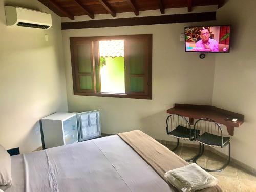卡皮托利乌Pousada e Camping Recanto da Praia的卧室配有一张床,墙上配有电视。