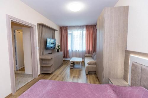 桑丹斯基Family Hotel Ambrozia的客房设有床、电视和沙发。