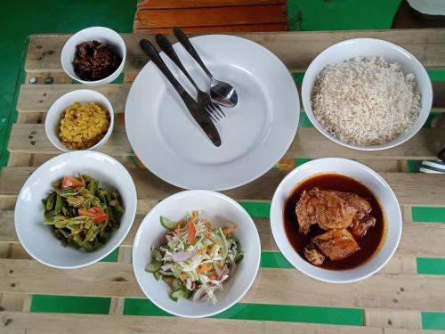 阿鲁甘湾Surf And Stay Arugam Bay的餐桌,盘子上放着食物和碗