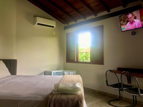 卡皮托利乌Pousada e Camping Recanto da Praia的卧室配有一张床,墙上配有电视。