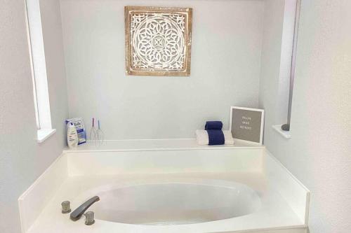 达拉斯Vacation Home with Private Pool的白色的浴室设有浴缸,墙上挂着一幅画