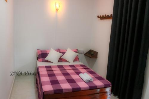 尼甘布Jaya Villa的卧室配有粉红色和紫色的可拉式床