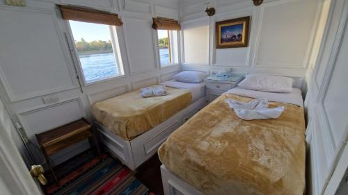 卢克索Dahabiya Nile Cruise的小房间设有两张床和窗户