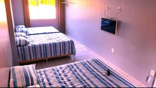 帕罗卡Recanto Munik的客房设有两张床和一台墙上的电视。