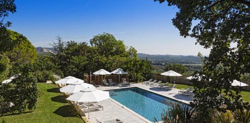 莱博德普罗旺斯马斯戴格雷酒店的游泳池旁配有白色遮阳伞和椅子